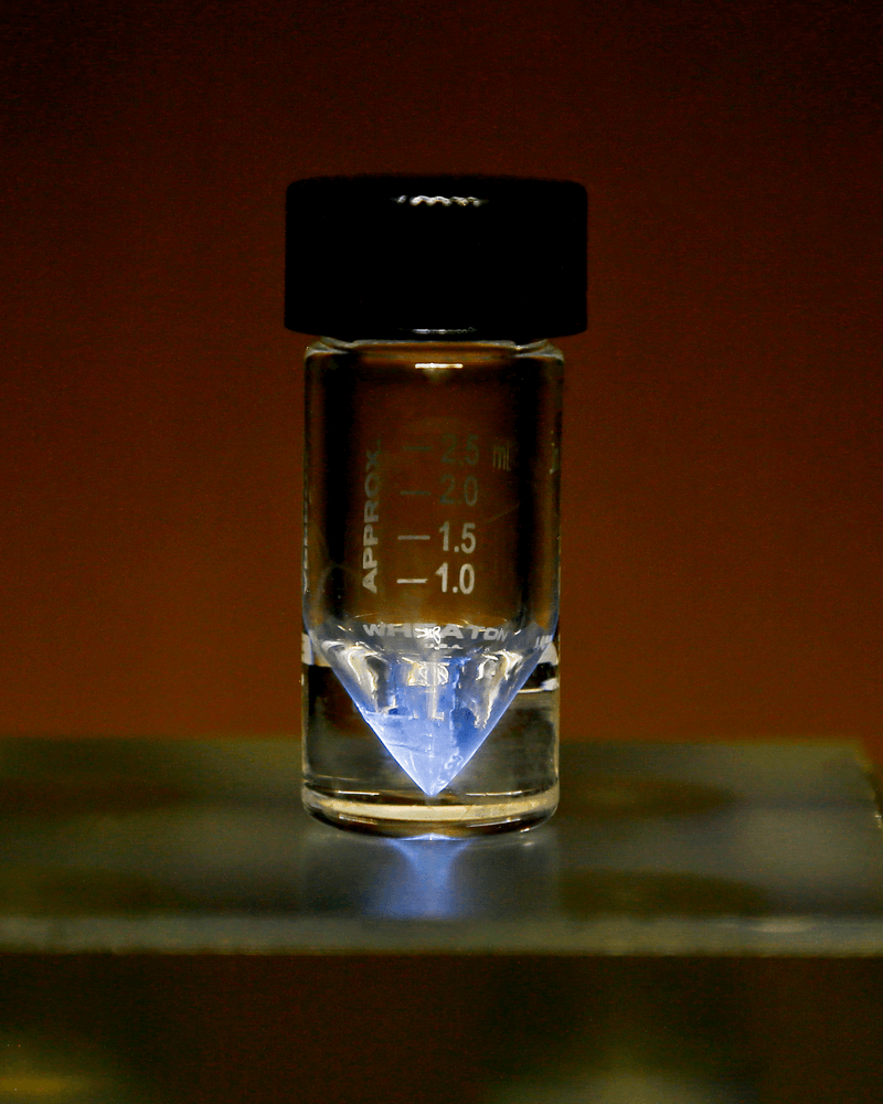 Actinium-225 medical radioisotope held in a v-vial at ORNL. Note the blue glow that originates from the ionization of surrounding air by alpha particles.